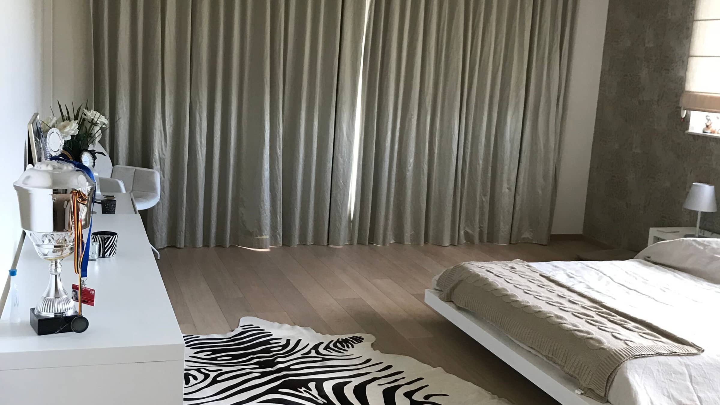 Chambre terminée après rénovation intérieure — parquet clair posé, rideaux toute hauteur et revêtement mural texturé