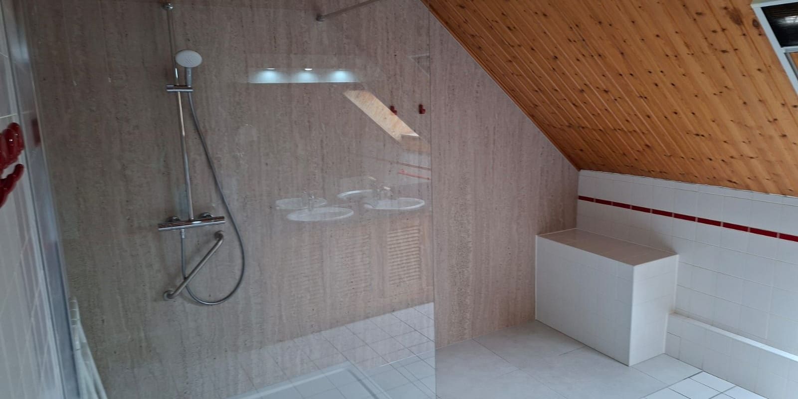 Douche à l’italienne sous rampant — receveur extra-plat, paroi vitrée, banc d’assise, barre d’appui et siège rabattable